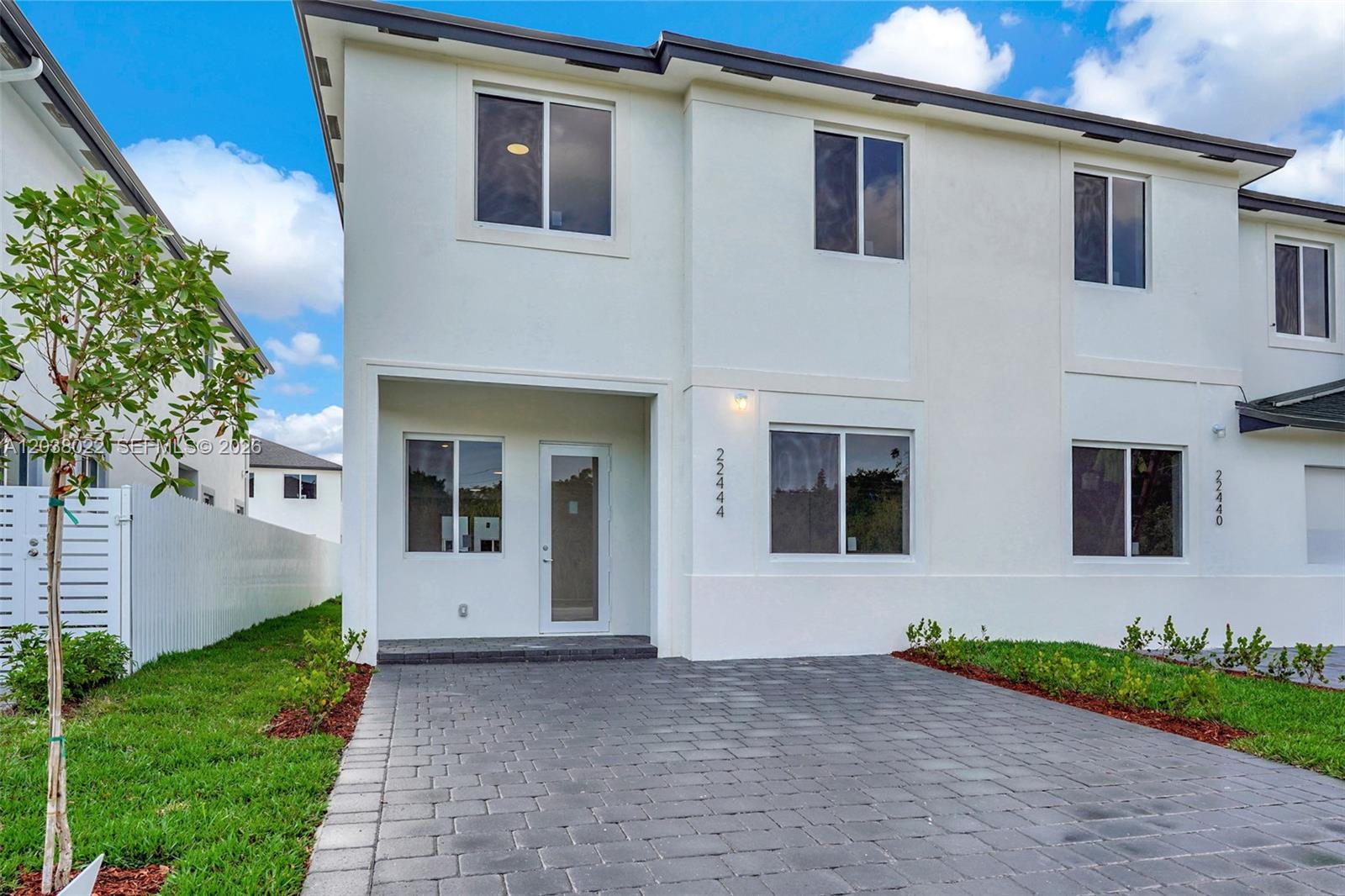 A two-story white stucco townhouse features a paved driveway and a recessed front entrance — 22505 SW 125th Ave, Miami FL 33170, MIAMI, FL