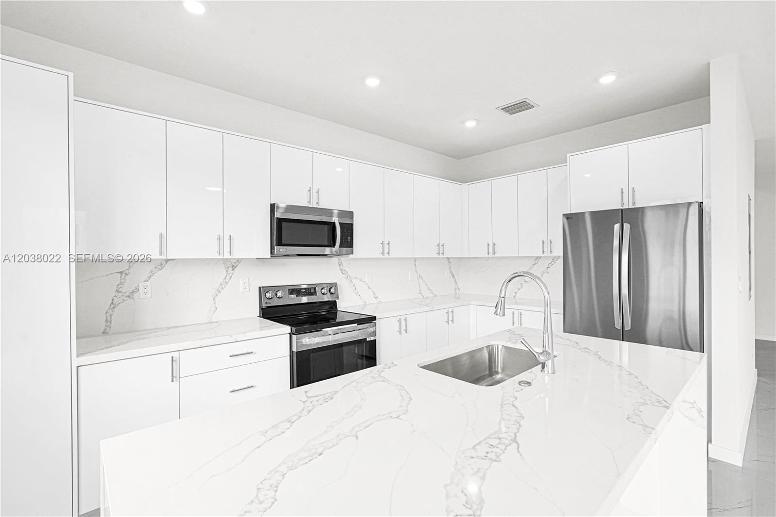 A modern kitchen features white cabinets, marble-patterned countertops, and stainless steel appliances — 22505 SW 125th Ave, Miami FL 33170, MIAMI, FL