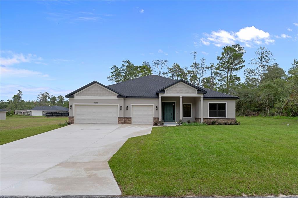 A single-story house with a two-car garage, gray siding, and a dark shingled roof — 8065 N DOTHAN DRIVE, DUNNELLON, FL