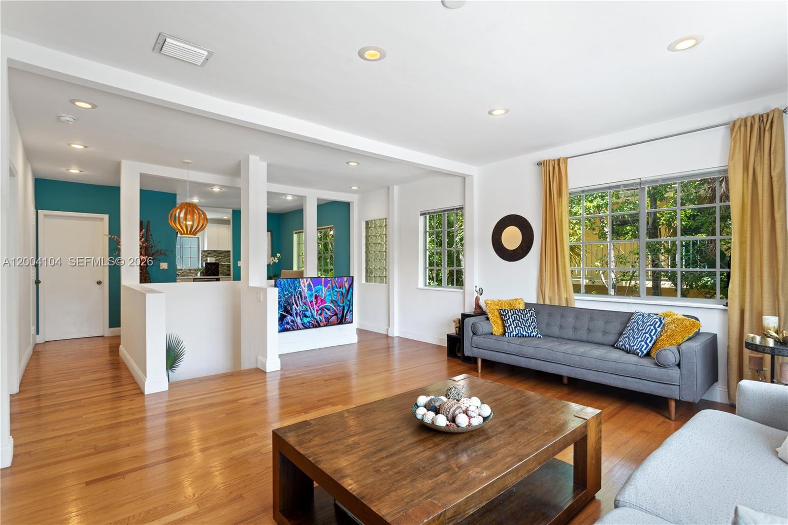 A living room features hardwood floors, a gray sofa, and a wall-mounted television — 840 Lenox Ave # 2, Miami Beach FL 33139, MIAMI BEACH, FL
