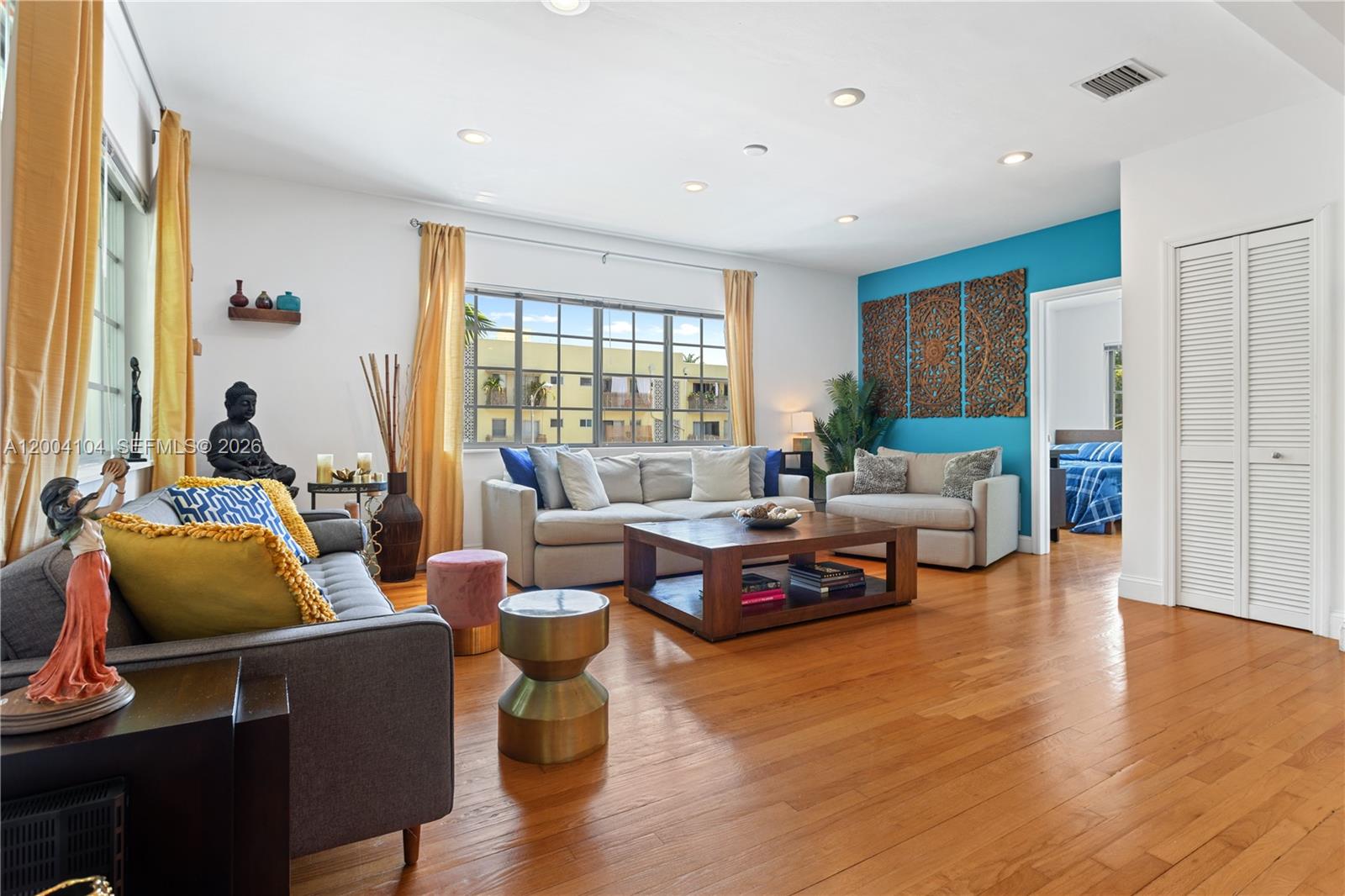 A living room features hardwood floors, a blue accent wall with wood art, and seating — 840 Lenox Ave # 2, Miami Beach FL 33139, MIAMI BEACH, FL