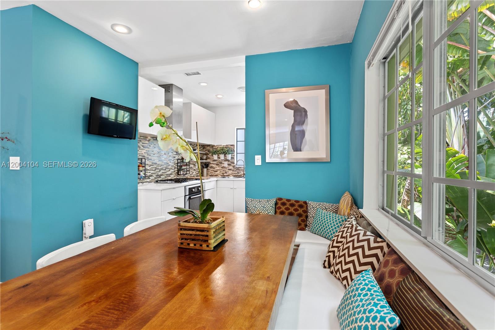 A dining area with a wooden table and built-in bench seating beside a kitchen — 840 Lenox Ave # 2, Miami Beach FL 33139, MIAMI BEACH, FL