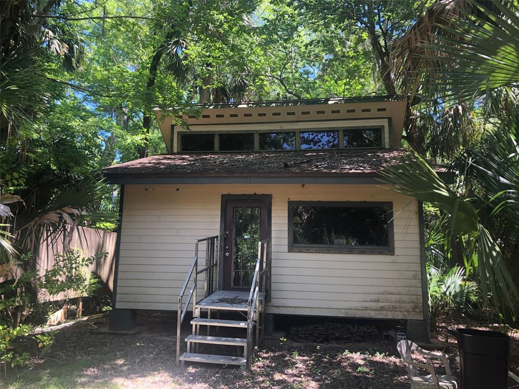 A small, elevated wooden cabin with a shed roof and clerestory windows sits among trees — 241 NOVA DRIVE, SANFORD, FL