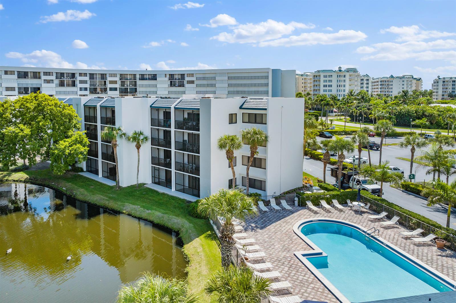 An exterior view of a multi-story apartment building with a swimming pool and pond — 1605 S Us Highway 1 # A106, Jupiter FL 33477, JUPITER, FL