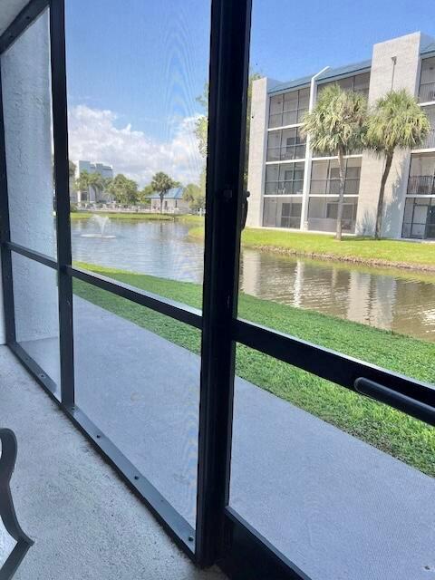 A view of a pond and apartment building seen through a screened-in patio door — 1605 S Us Highway 1 # A106, Jupiter FL 33477, JUPITER, FL