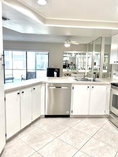 A kitchen features white cabinets, stainless steel appliances, and light-colored tile flooring — 1605 S Us Highway 1 # A106, Jupiter FL 33477, JUPITER, FL