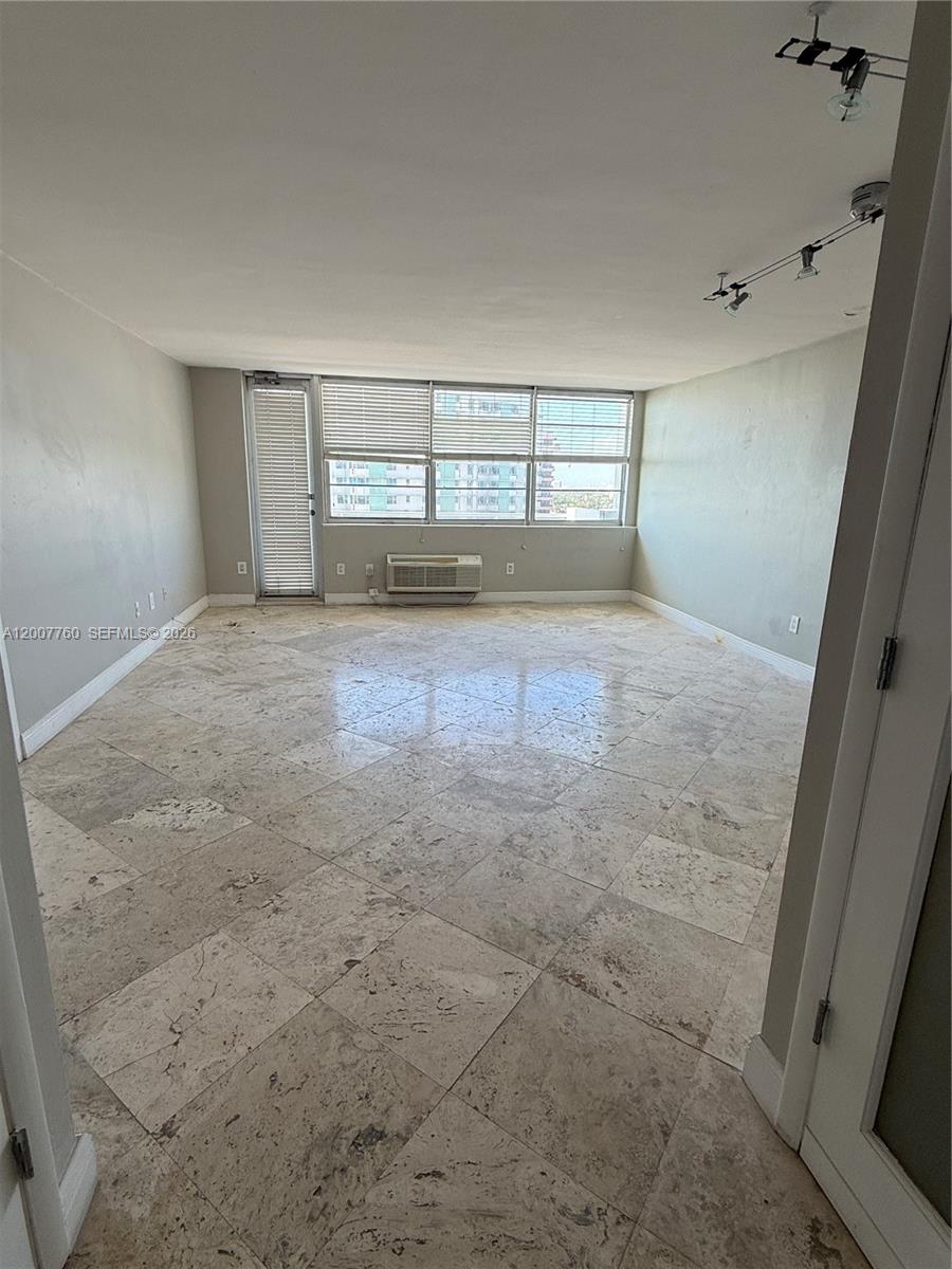 An empty room features large beige floor tiles, a window wall, and a balcony door — 5313 Collins Ave # 1110, Miami Beach FL 33140, MIAMI BEACH, FL