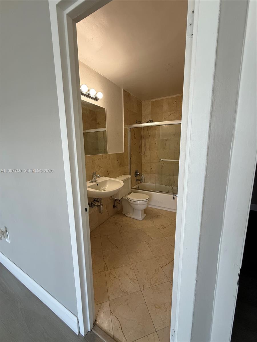 A bathroom features a pedestal sink, a toilet, and a shower-tub combo with tiled walls — 5313 Collins Ave # 1110, Miami Beach FL 33140, MIAMI BEACH, FL