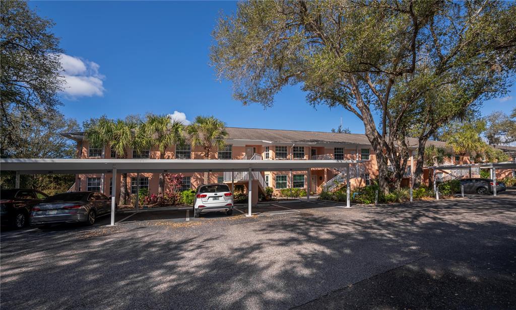 A two-story apartment building with a covered parking area and mature trees in front — 19300 WATER OAK DRIVE UNIT 102, PORT CHARLOTTE, FL