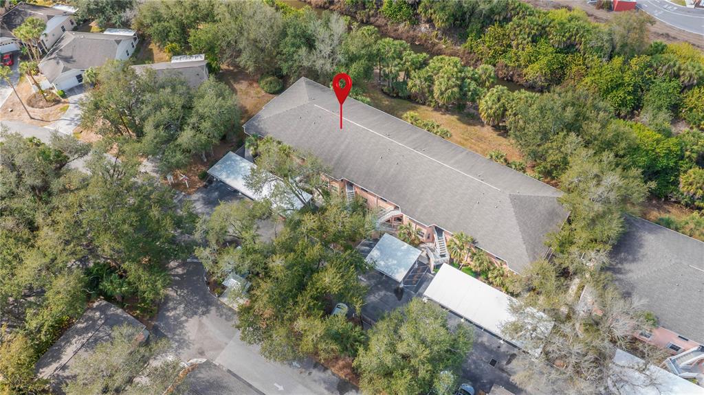An aerial view shows a multi-story apartment building surrounded by trees and covered parking — 19300 WATER OAK DRIVE UNIT 102, PORT CHARLOTTE, FL