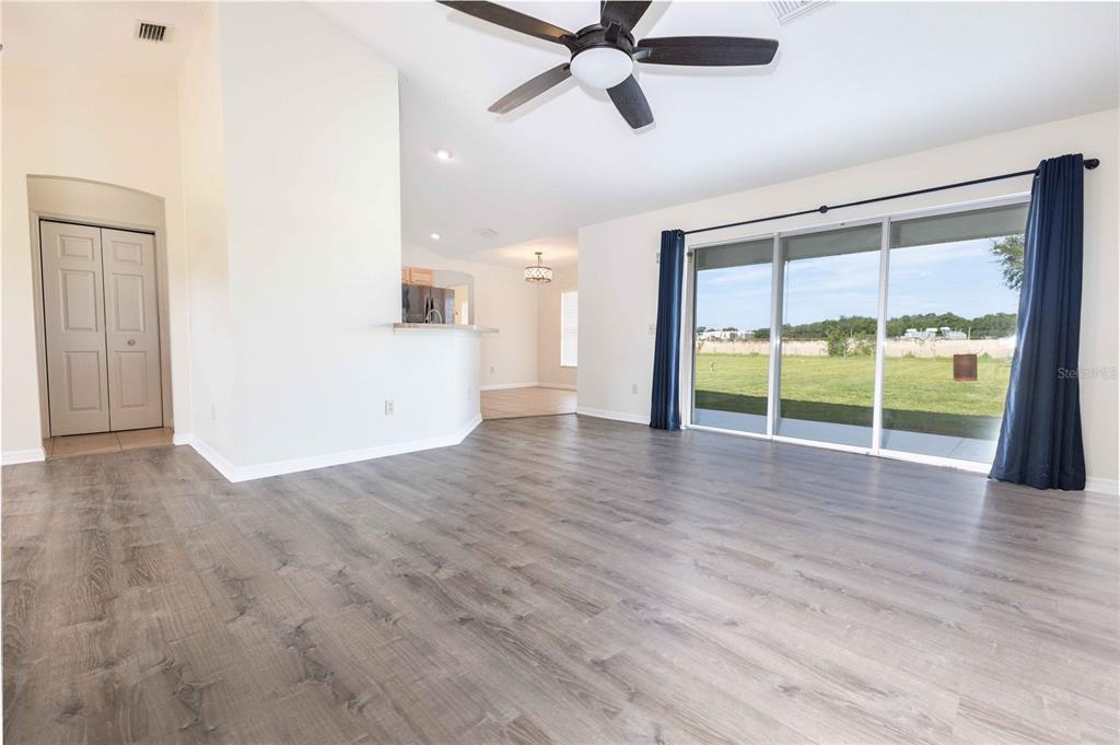 A living room with wood-look flooring, a ceiling fan, and sliding glass doors to a yard — 9170 COUNTY ROAD 128D ROAD, WILDWOOD, FL