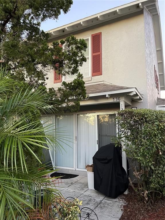 A two-story building exterior features a patio with sliding glass doors and a covered entrance — 1222 VILLA LANE UNIT 136, APOPKA, FL