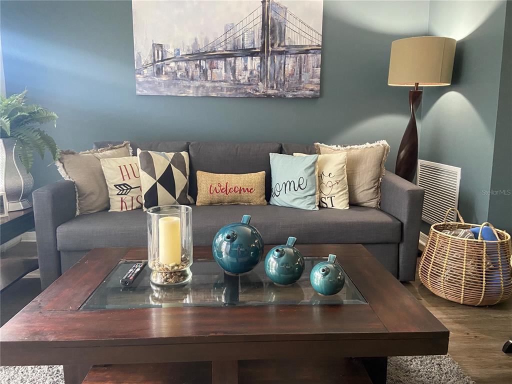 A living room features a gray sofa with decorative pillows, a coffee table, and artwork — 1222 VILLA LANE UNIT 136, APOPKA, FL