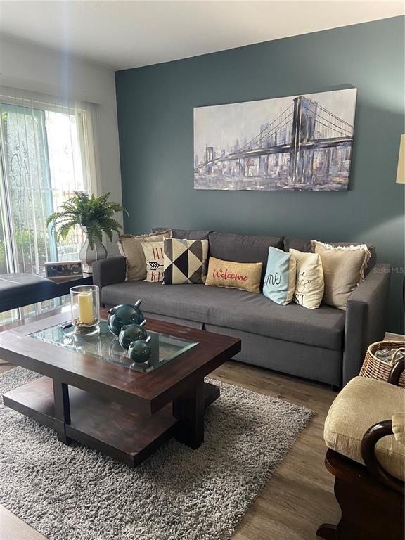 A living room features a dark gray sofa, a wooden coffee table, and bridge artwork — 1222 VILLA LANE UNIT 136, APOPKA, FL