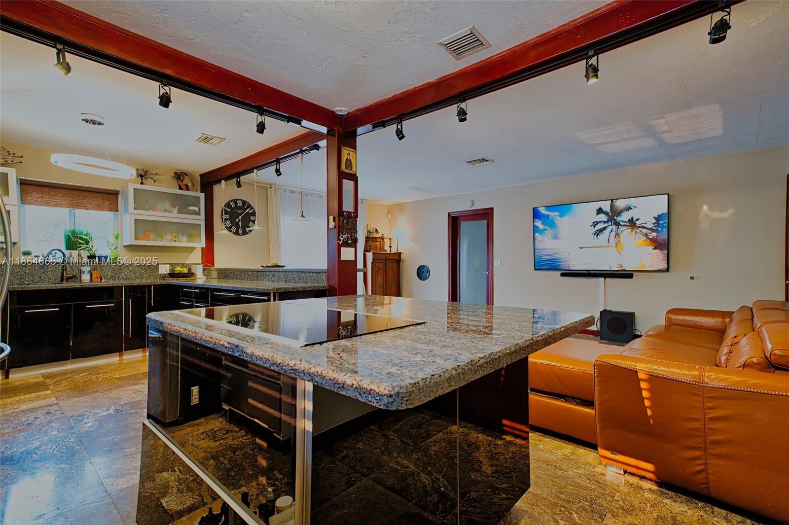 A kitchen with granite countertops and a central island opens into a living room area — 1923 Dewey St, Hollywood FL 33020, HOLLYWOOD, FL