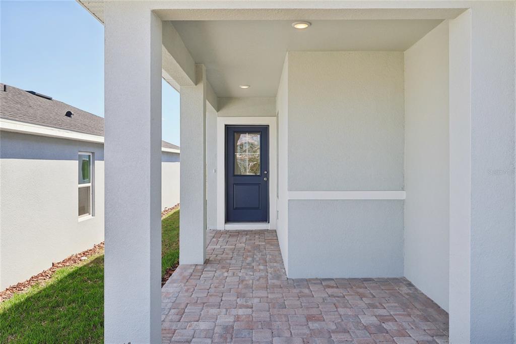 A covered entryway features a blue front door, recessed lighting, and a paved brick floor — 1925 DIAMOND HEAD CIRCLE, HAINES CITY, FL