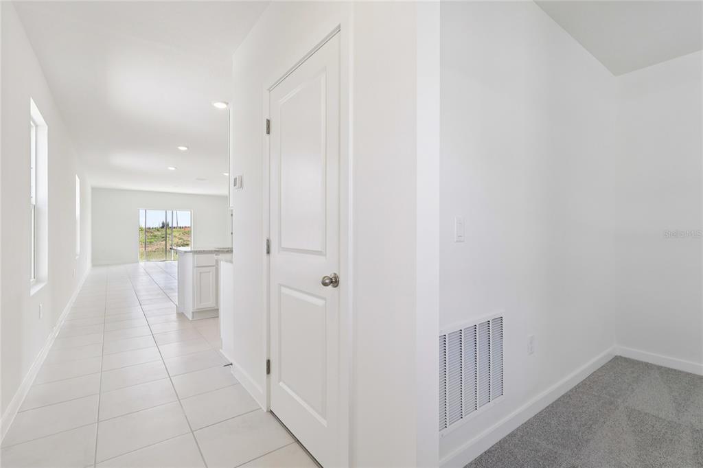 A hallway with tile flooring leads to a kitchen, with a carpeted room to the right — 1925 DIAMOND HEAD CIRCLE, HAINES CITY, FL