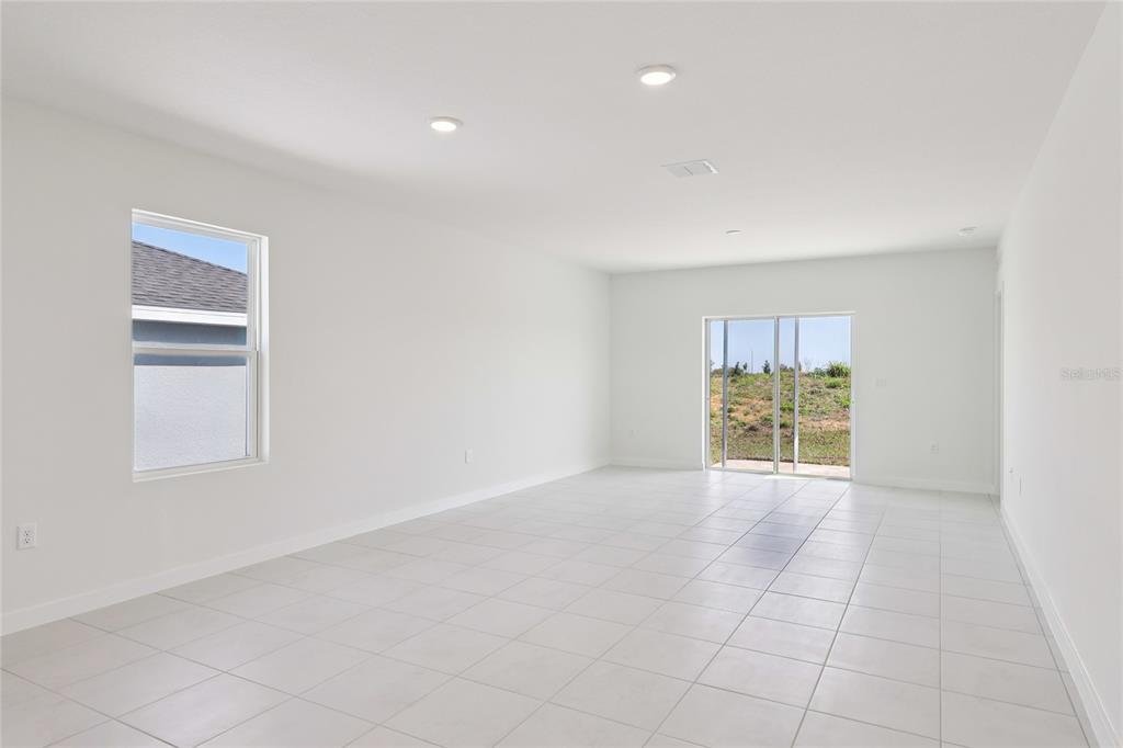 An empty room with white walls, tiled floors, recessed lighting, and a sliding glass door — 1925 DIAMOND HEAD CIRCLE, HAINES CITY, FL