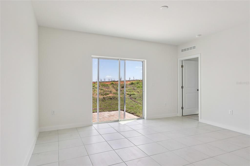 A bright room with white walls, tiled flooring, and sliding glass doors leading outside — 1925 DIAMOND HEAD CIRCLE, HAINES CITY, FL