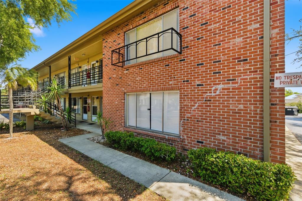 Exterior view of a two-story brick apartment building with a walkway and staircase — 1257 DREW STREET UNIT 14, CLEARWATER, FL