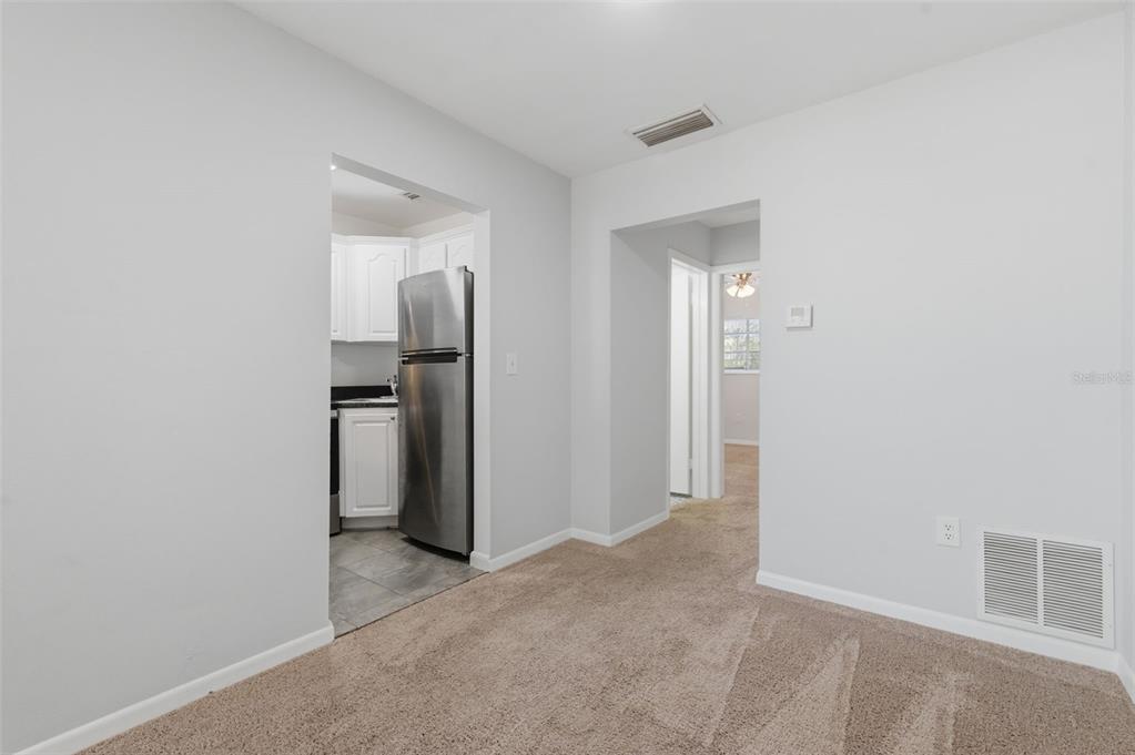 A carpeted room leads into a kitchen with stainless steel appliances and tile flooring — 1257 DREW STREET UNIT 14, CLEARWATER, FL