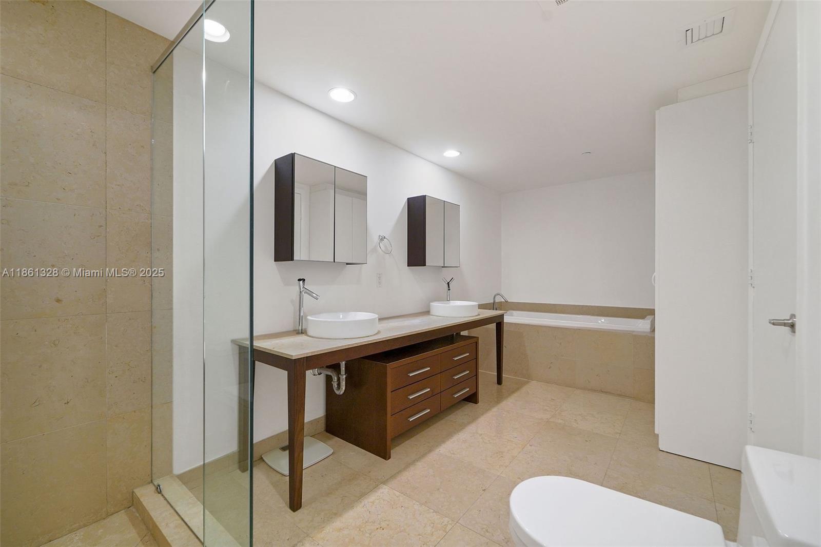 A modern bathroom features a double vanity with vessel sinks, a glass-enclosed shower, and a tub — 495 Brickell Ave # 402, Miami FL 33131, MIAMI, FL