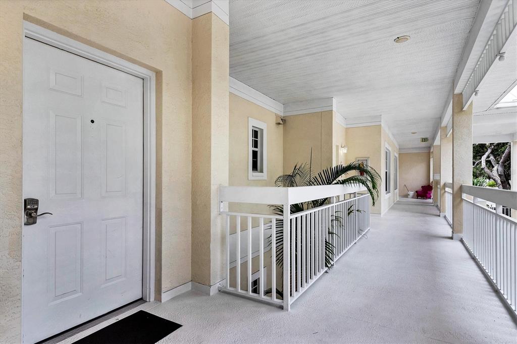 An exterior hallway with a white door, white railings, and a concrete floor — 3702 54TH DRIVE W UNIT 203, BRADENTON, FL