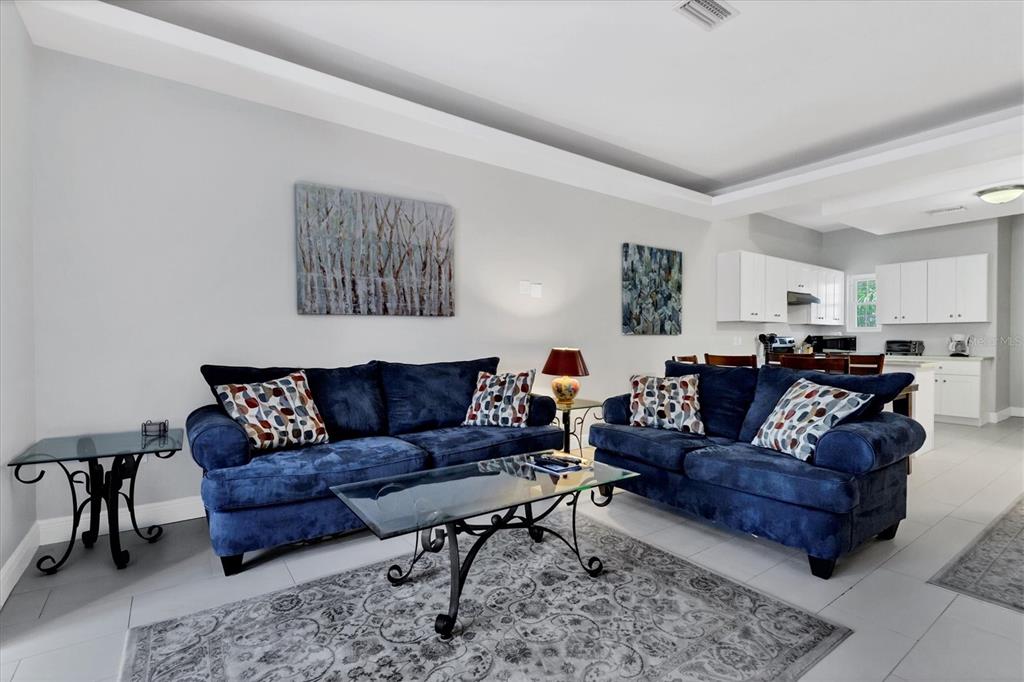 A living room features two blue sofas, a glass coffee table, and an open kitchen — 3702 54TH DRIVE W UNIT 203, BRADENTON, FL