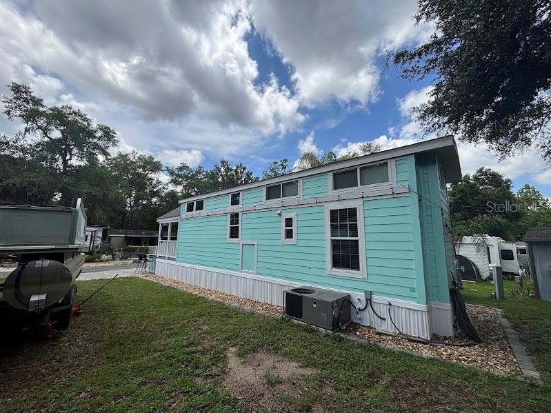 A light blue tiny home sits on a gravel lot next to a trailer — 25229 NE 142ND STREET UNIT 229, FORT MC COY, FL