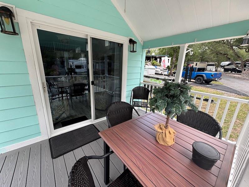 A covered porch features a wooden table, black chairs, and a sliding glass door — 25229 NE 142ND STREET UNIT 229, FORT MC COY, FL