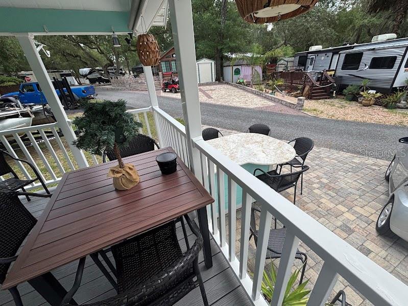 A covered porch features a wooden dining table and a patio set overlooking a driveway — 25229 NE 142ND STREET UNIT 229, FORT MC COY, FL