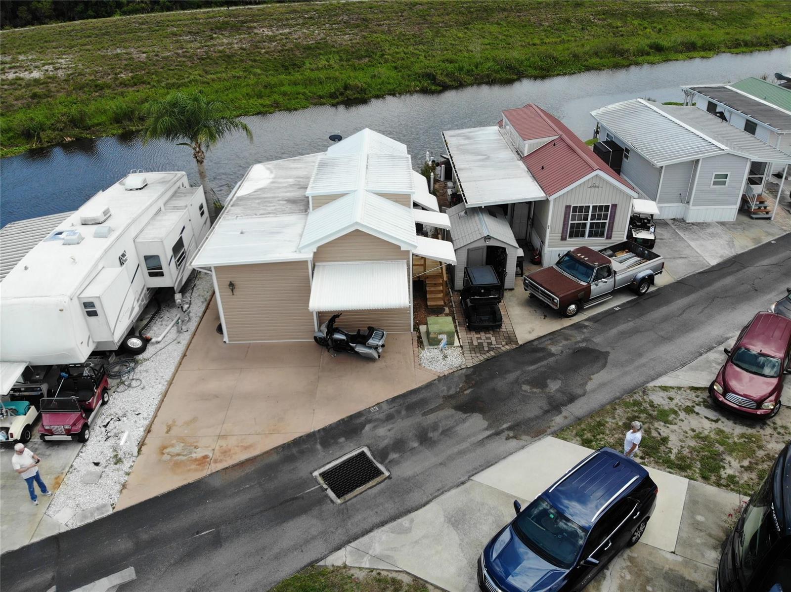 An aerial view shows several mobile homes, parked vehicles, and a canal in a neighborhood — 7950 State Road 78, Okeechobee FL 34974, OKEECHOBEE, FL