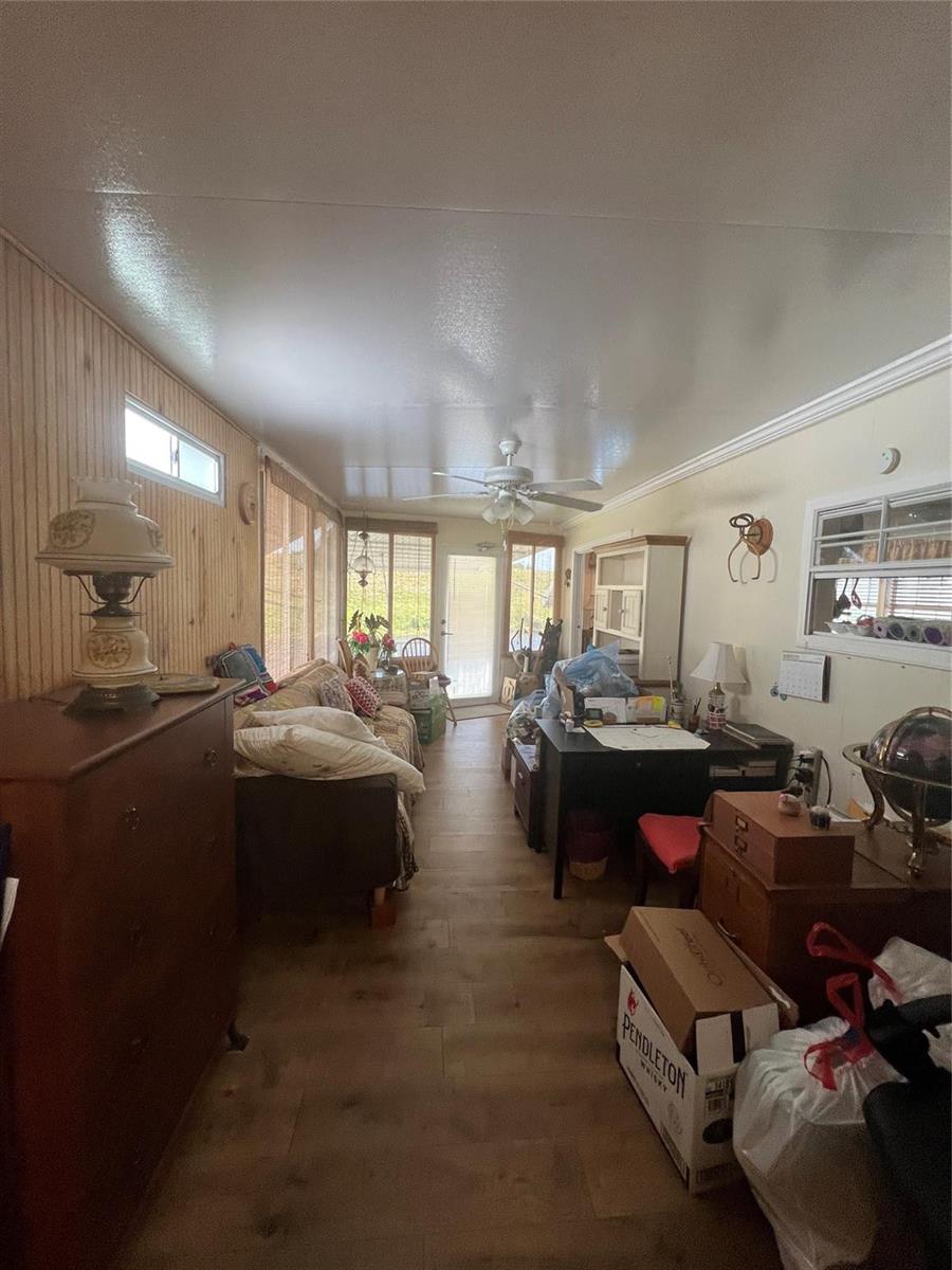 A long, narrow sunroom features wood-paneled walls, a ceiling fan, and a mix of furniture — 7950 State Road 78, Okeechobee FL 34974, OKEECHOBEE, FL