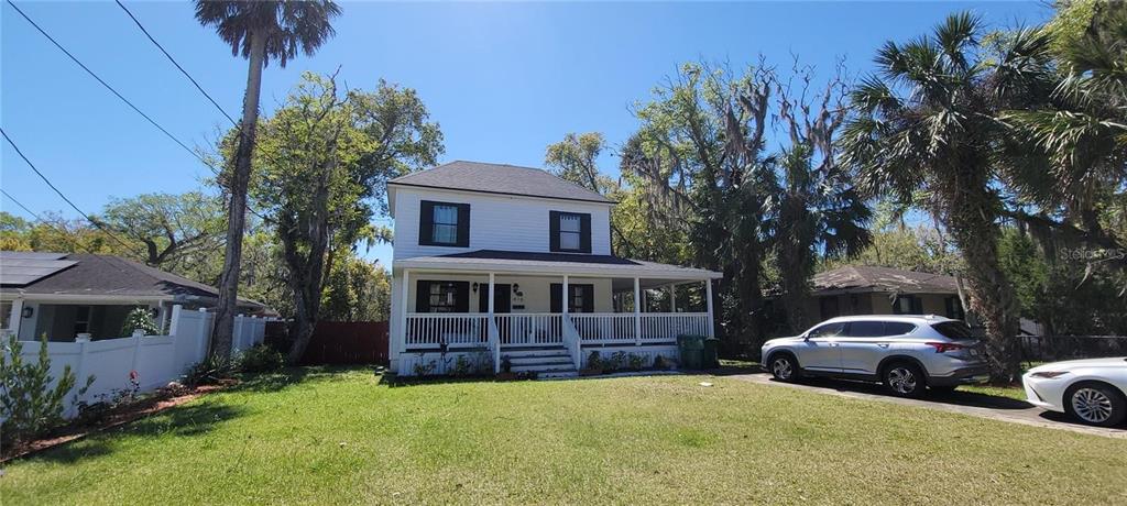 A two-story white house with a front porch and black shutters sits on a lawn — 416 W HOWRY, DELAND, FL