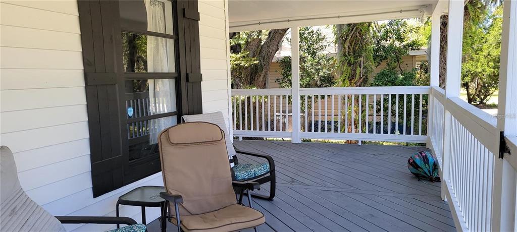A covered wooden porch features a white railing, two chairs, and a small side table — 416 W HOWRY, DELAND, FL