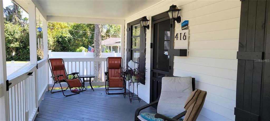 A covered front porch features gray decking, white railings, and several outdoor chairs — 416 W HOWRY, DELAND, FL