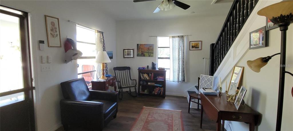 A living room features a dark leather armchair, a wooden bookshelf, and a staircase — 416 W HOWRY, DELAND, FL