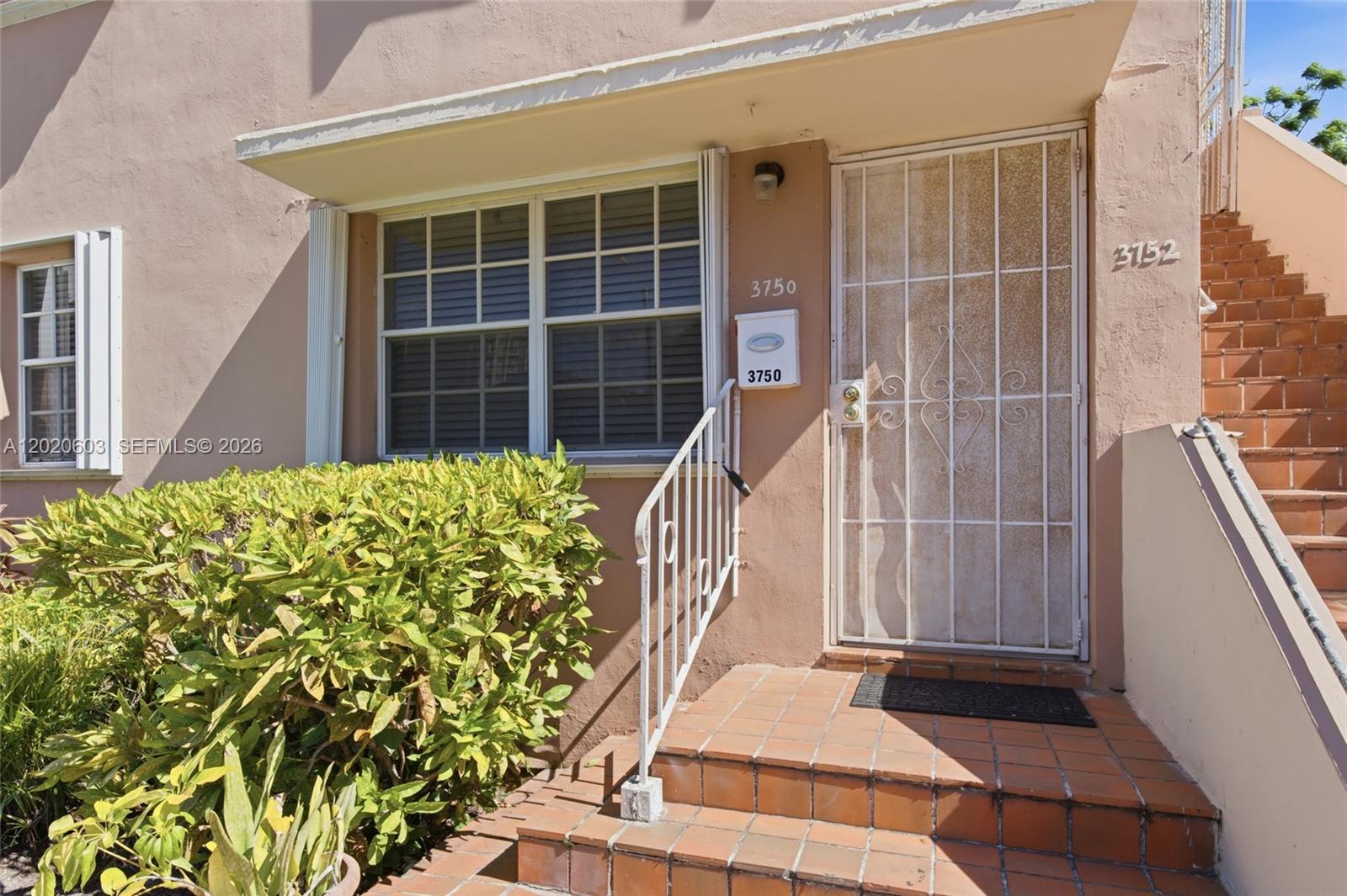 The exterior of a tan building features a front door with a security gate — 3750 SW 27th St, Miami FL 33134, MIAMI, FL