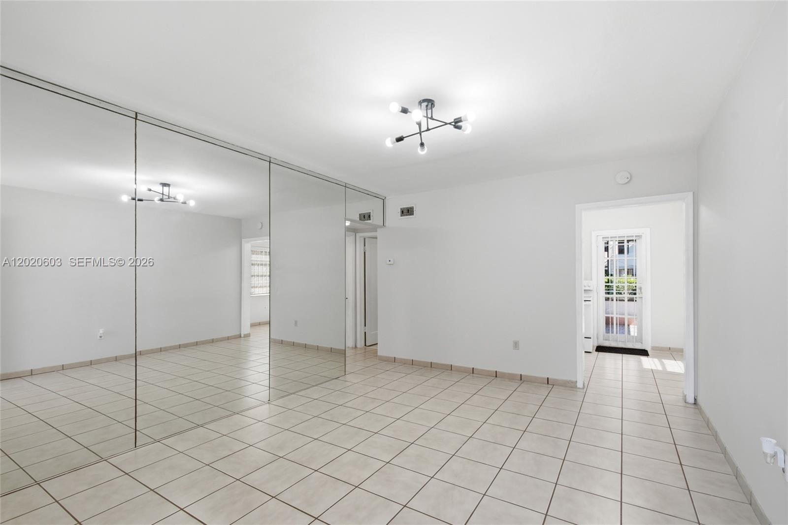 A room with white walls, tiled floors, a modern light fixture, and a mirrored wall — 3750 SW 27th St, Miami FL 33134, MIAMI, FL