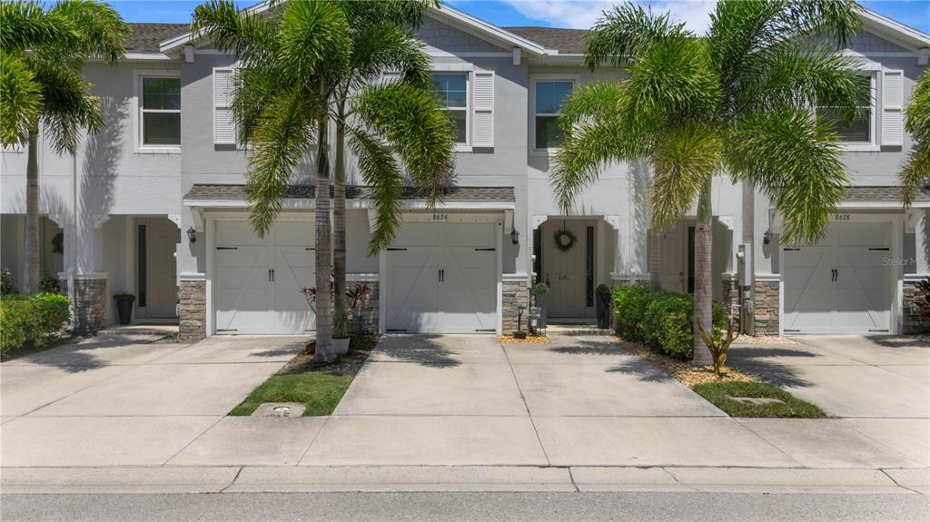 A row of two-story townhomes with white garage doors, concrete driveways, and palm trees — 8624 STARGAZER STREET, SARASOTA, FL