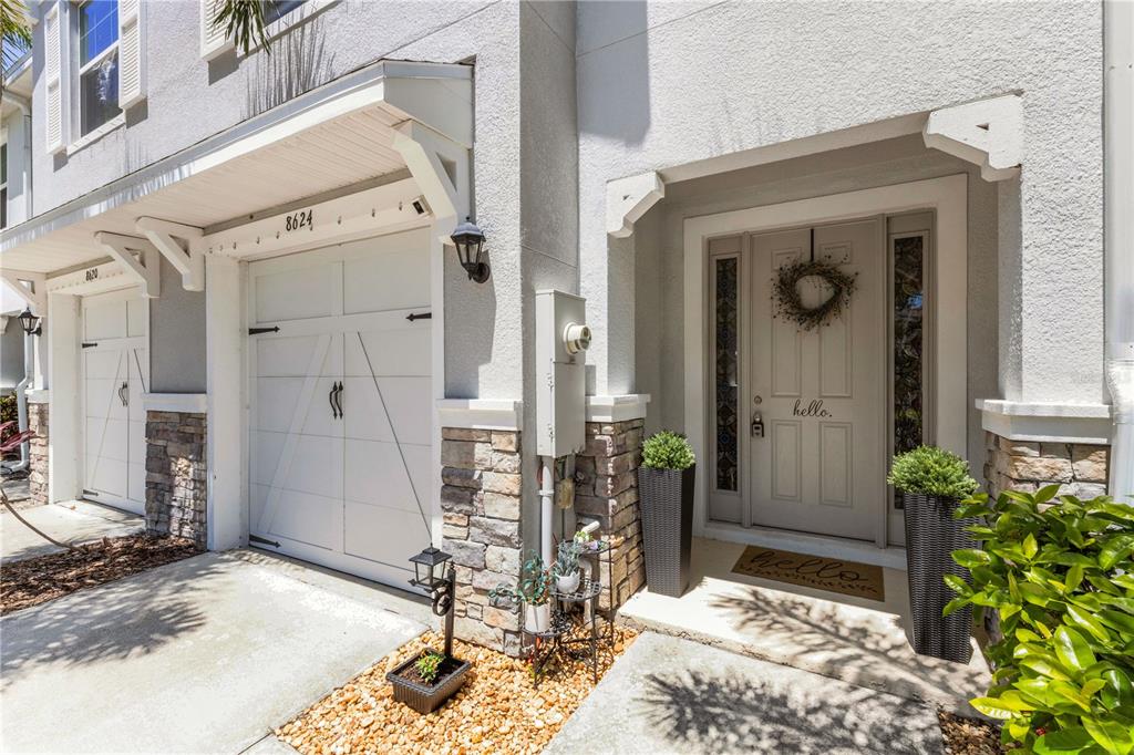 The exterior of a townhouse features a white garage, a stone-accented entryway, and a front door — 8624 STARGAZER STREET, SARASOTA, FL
