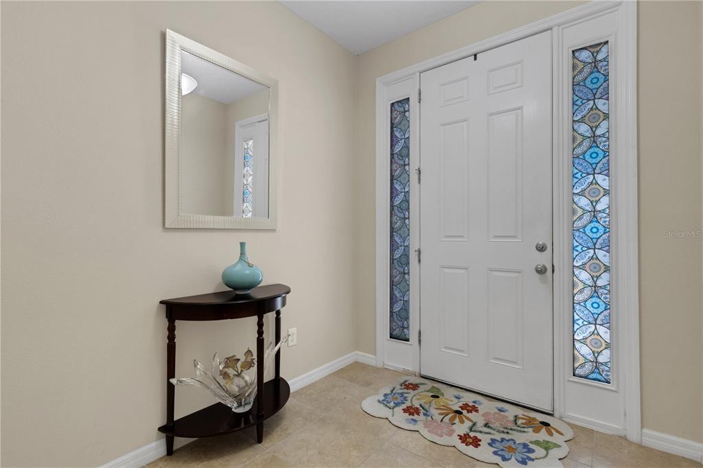 An entryway features a white front door with stained glass sidelights, a mirror, and console table — 8624 STARGAZER STREET, SARASOTA, FL