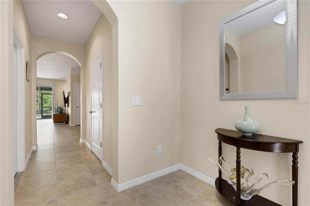 An entryway features tile flooring, a half-moon console table with a mirror, and an arched hallway — 8624 STARGAZER STREET, SARASOTA, FL