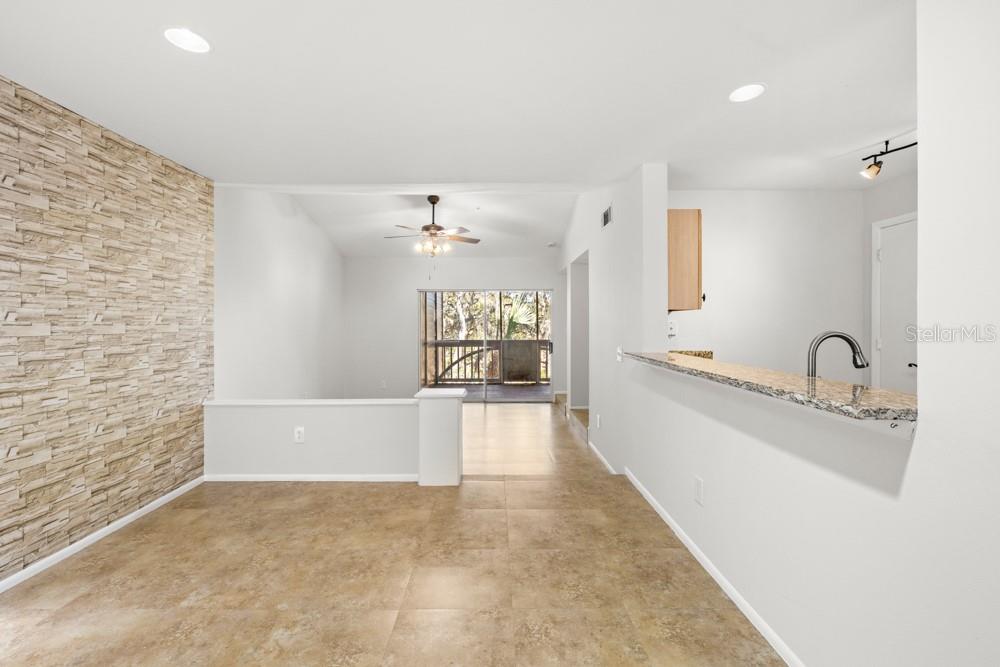 A dining area with a stone-look accent wall, tile flooring, and a kitchen breakfast bar — 486 N PIN OAK PLACE UNIT 308, LONGWOOD, FL