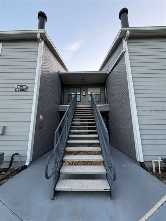 An exterior view of a multi-story apartment building with a central staircase leading to units — 3708 IDLEBROOK CIRCLE UNIT 212, CASSELBERRY, FL