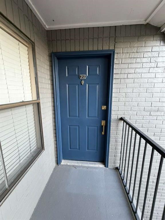 A blue apartment door with the number 212 is set in a gray brick wall — 3708 IDLEBROOK CIRCLE UNIT 212, CASSELBERRY, FL