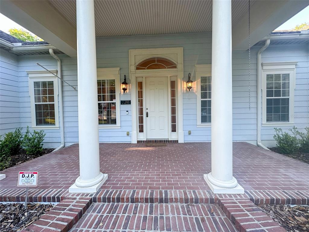 A light blue house features a brick porch with two large white columns — 6425 NW 202ND PLACE, MICANOPY, FL
