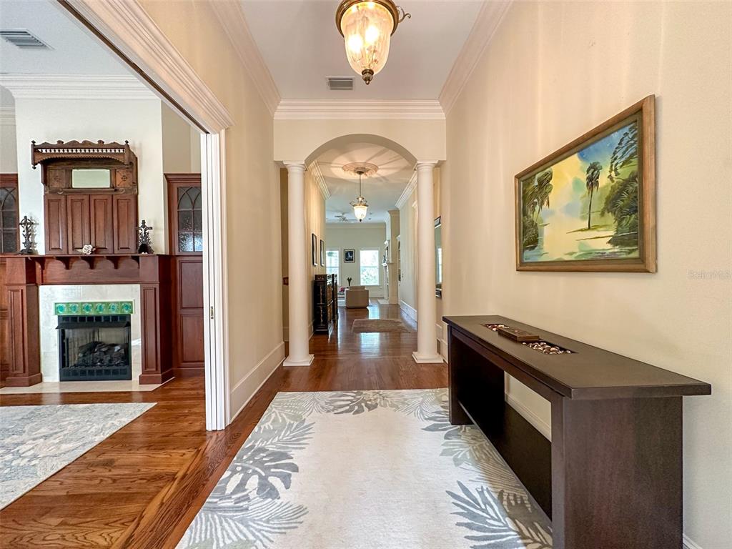 A hallway with hardwood floors, a console table, and an arched entryway leading to another room — 6425 NW 202ND PLACE, MICANOPY, FL