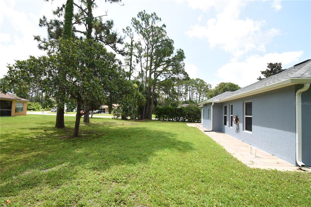 A side view of a gray house with a lawn and tall pine trees — 192 PINE GROVE DRIVE, PALM COAST, FL