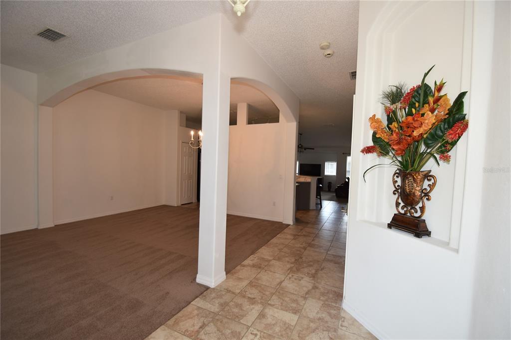 An interior view shows a tiled entryway with an arched wall niche and carpeted living area — 192 PINE GROVE DRIVE, PALM COAST, FL